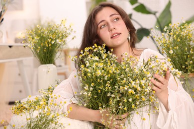 Photo of Portrait of beautiful woman with chamomile flowers indoors