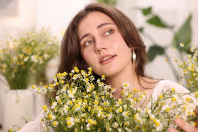 Photo of Portrait of beautiful woman with chamomile flowers indoors