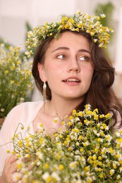 Photo of Portrait of beautiful woman with chamomile flowers indoors