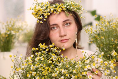 Photo of Portrait of beautiful woman with chamomile flowers indoors