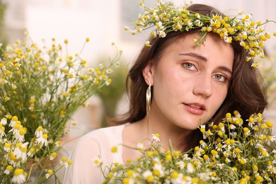 Photo of Portrait of beautiful woman with chamomile flowers indoors