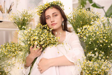 Photo of Portrait of beautiful woman with chamomile flowers indoors