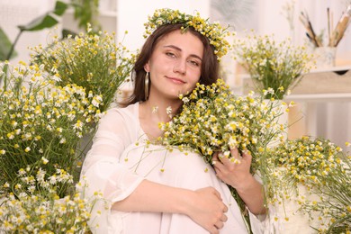 Photo of Portrait of beautiful woman with chamomile flowers indoors
