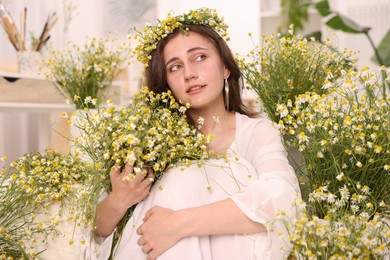 Photo of Portrait of beautiful woman with chamomile flowers indoors