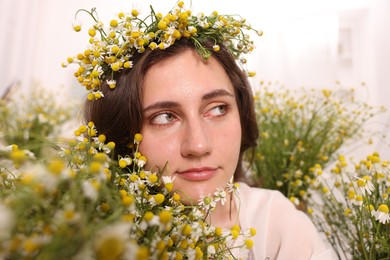 Photo of Portrait of beautiful woman with chamomile flowers indoors
