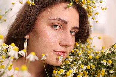 Photo of Portrait of beautiful woman with chamomile flowers indoors