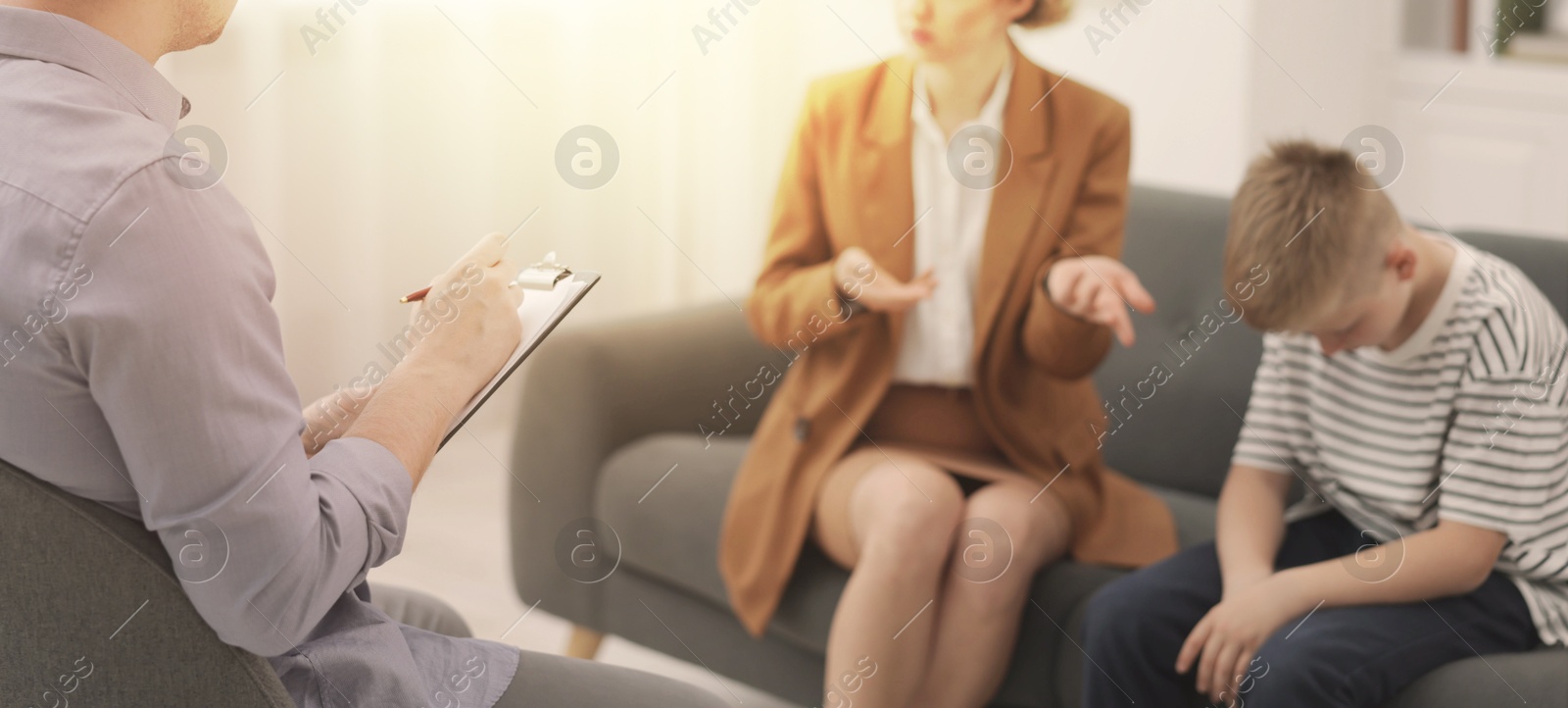 Psychologist working with mother and son in office Image of Psychologist working with mother and son in office