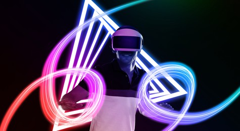 Image of Man using virtual reality headset on black background. Bright neon lines near him
