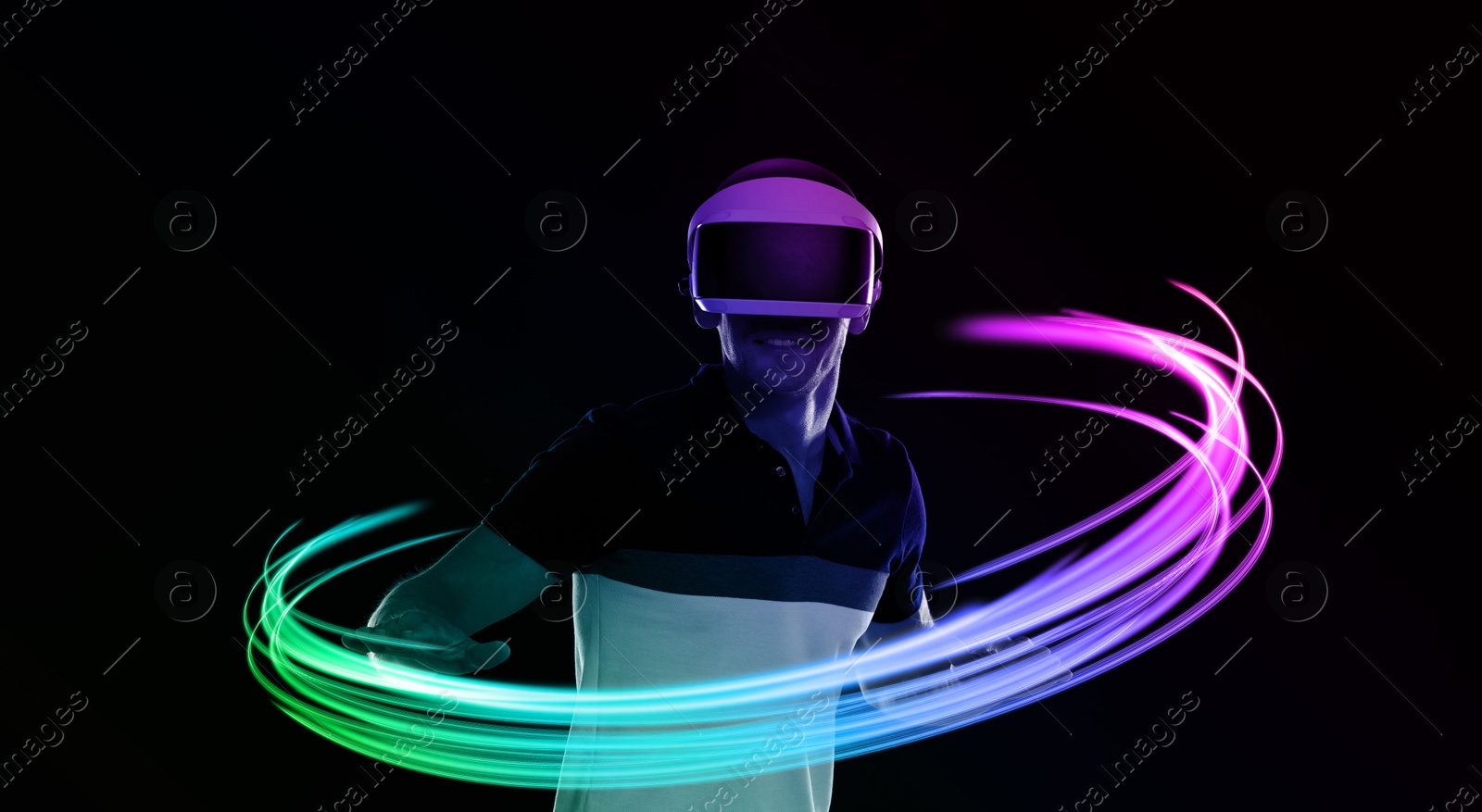 Man using virtual reality headset on black background. Bright neon lines around him Image of Man using virtual reality headset on black background. Bright neon lines around him