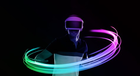 Image of Man using virtual reality headset on black background. Bright neon lines around him