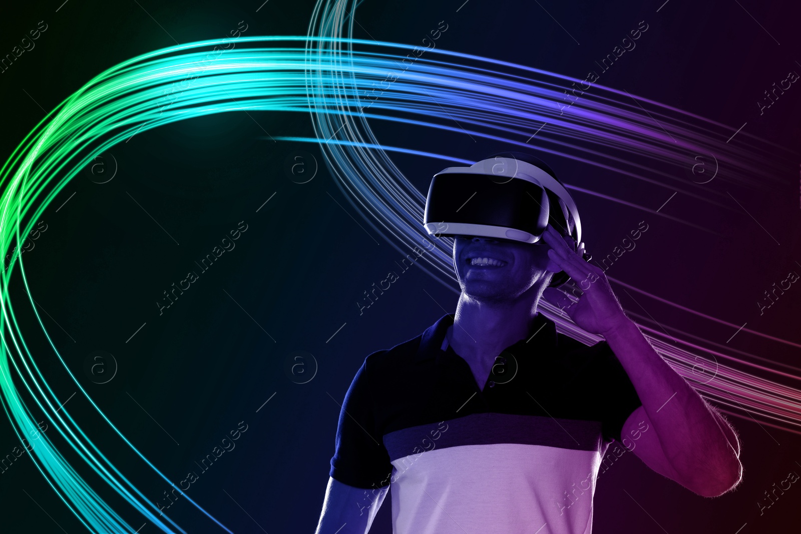 Man using virtual reality headset on black background. Bright neon lines around him Image of Man using virtual reality headset on black background. Bright neon lines around him