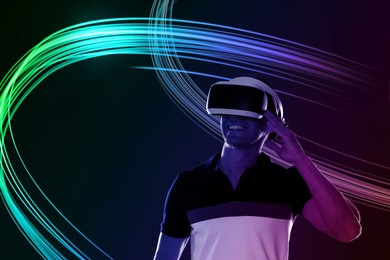 Image of Man using virtual reality headset on black background. Bright neon lines around him