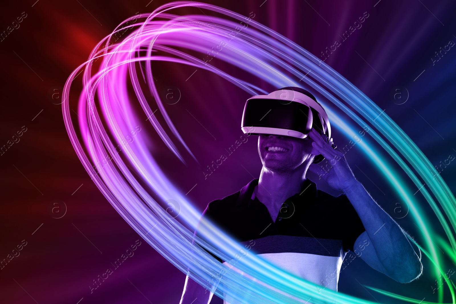 Man using virtual reality headset on colorful background. Bright neon lines around him Image of Man using virtual reality headset on colorful background. Bright neon lines around him