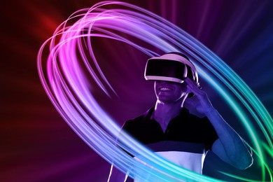 Image of Man using virtual reality headset on colorful background. Bright neon lines around him
