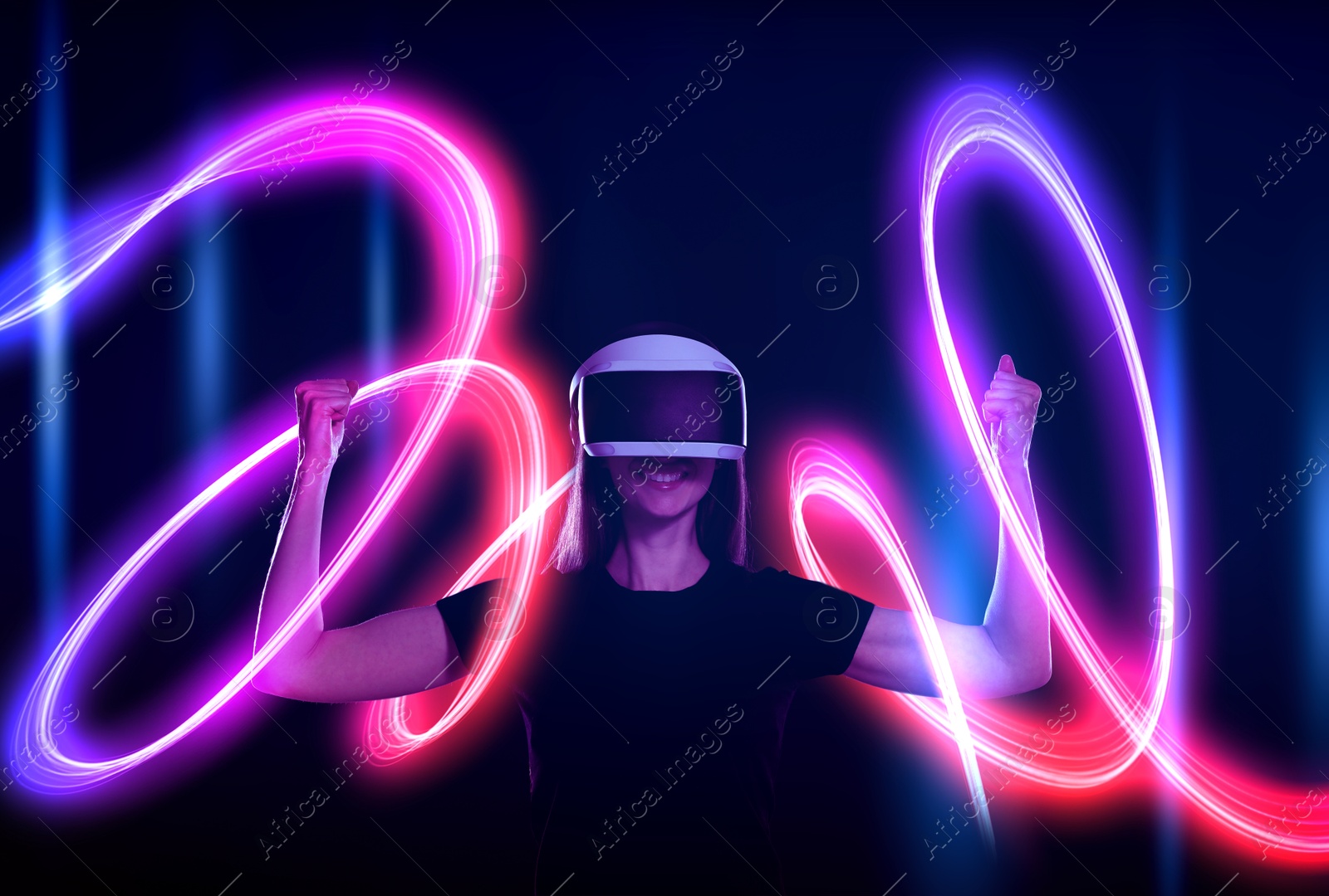 Woman using virtual reality headset on dark blue background. Bright neon line around her Image of Woman using virtual reality headset on dark blue background. Bright neon line around her