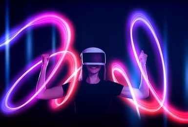 Image of Woman using virtual reality headset on dark blue background. Bright neon line around her