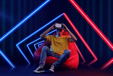 Image of Man using virtual reality headset on bean bag chair. Cyberspace in neon colors