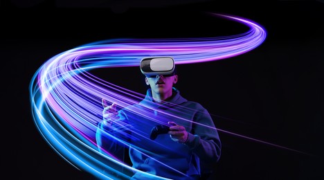Image of Man using virtual reality headset and controller against black background. Bright neon lines near him