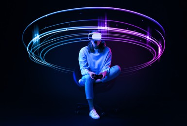 Image of Woman using virtual reality headset and controller against black background. Bright neon lines around her