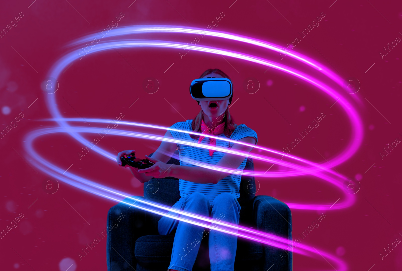 Woman using virtual reality headset and controller in armchair on crimson color background. Bright neon lines around her Image of Woman using virtual reality headset and controller in armchair on crimson color background. Bright neon lines around her