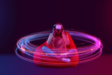 Image of Woman using virtual reality headset on bean bag chair against color background. Bright neon lines around her