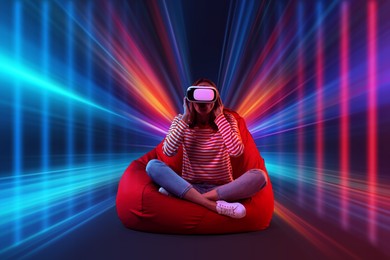 Image of Woman using virtual reality headset on bean bag chair. Cyberspace in neon colors