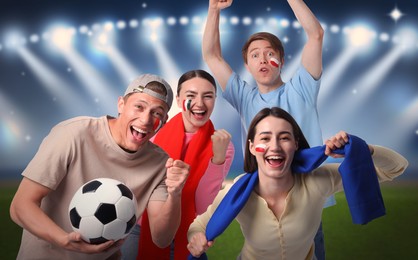 Image of Excited football fans with flags painted on their faces at stadium
