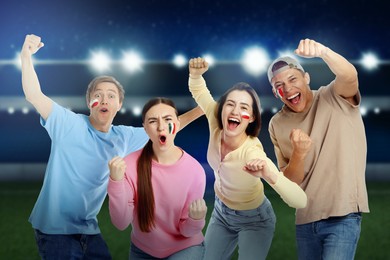 Image of Excited football fans with flags painted on their faces at stadium