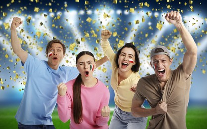 Image of Excited football fans with flags painted on their faces under falling confetti at stadium