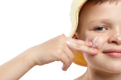 Photo of Little boy applying sun protection cream onto his skin on white background, closeup