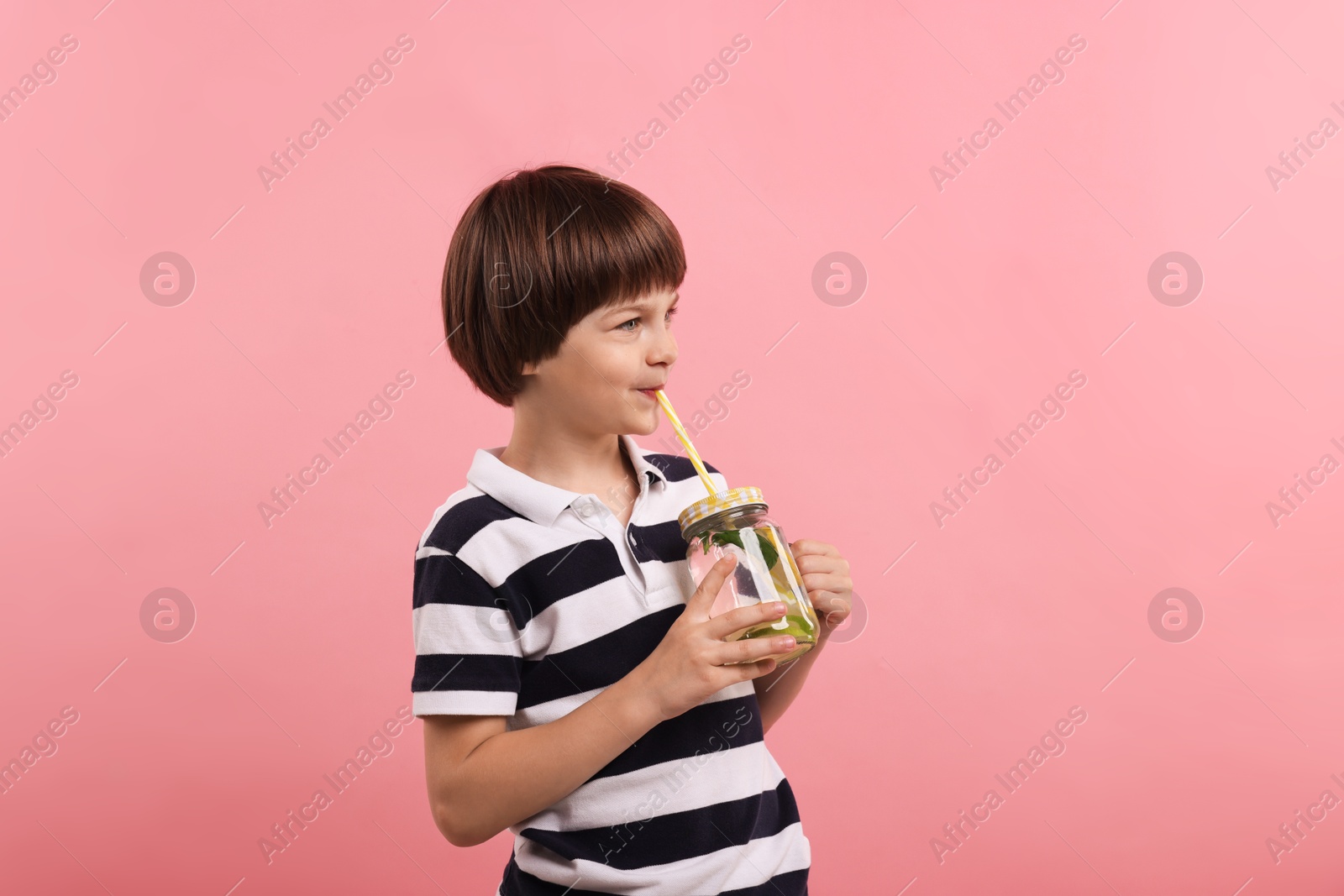 Cute little boy drinking lemonade on pink background. Refreshing drink Photo of Cute little boy drinking lemonade on pink background. Refreshing drink