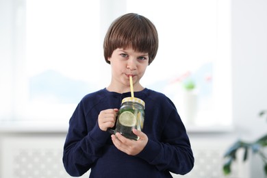 Photo of Cute little boy drinking lemonade at home. Refreshing drink