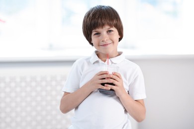 Photo of Cute little boy with glass of refreshing soda drink at home