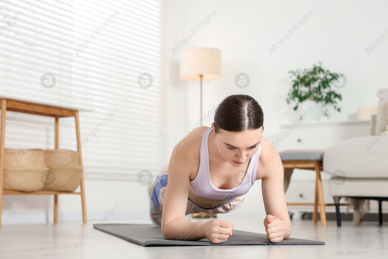 Young woman in sportswear doing plank exercise at home. Space for text Photo of Young woman in sportswear doing plank exercise at home. Space for text