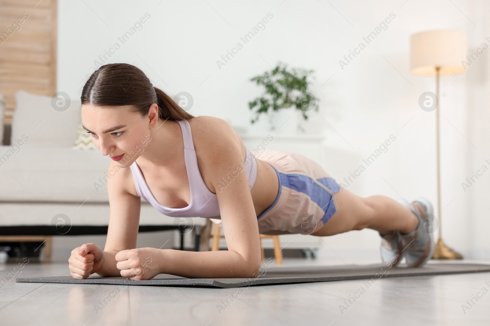 Young woman in sportswear doing plank exercise at home Photo of Young woman in sportswear doing plank exercise at home