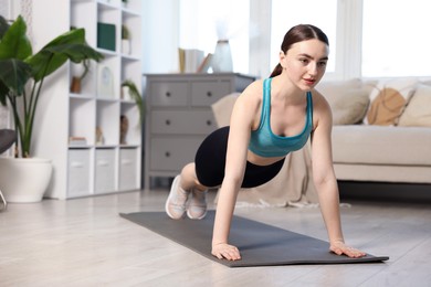 Photo of Young woman in sportswear doing plank exercise at home. Space for text