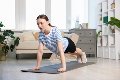 Photo of Sporty woman doing plank exercise at home