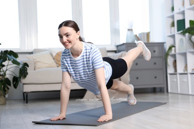 Photo of Smiling sporty woman doing plank exercise at home