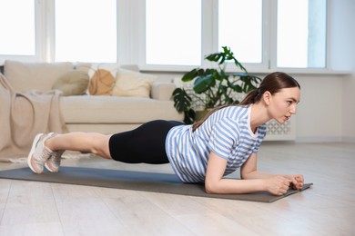 Photo of Sporty woman doing plank exercise at home