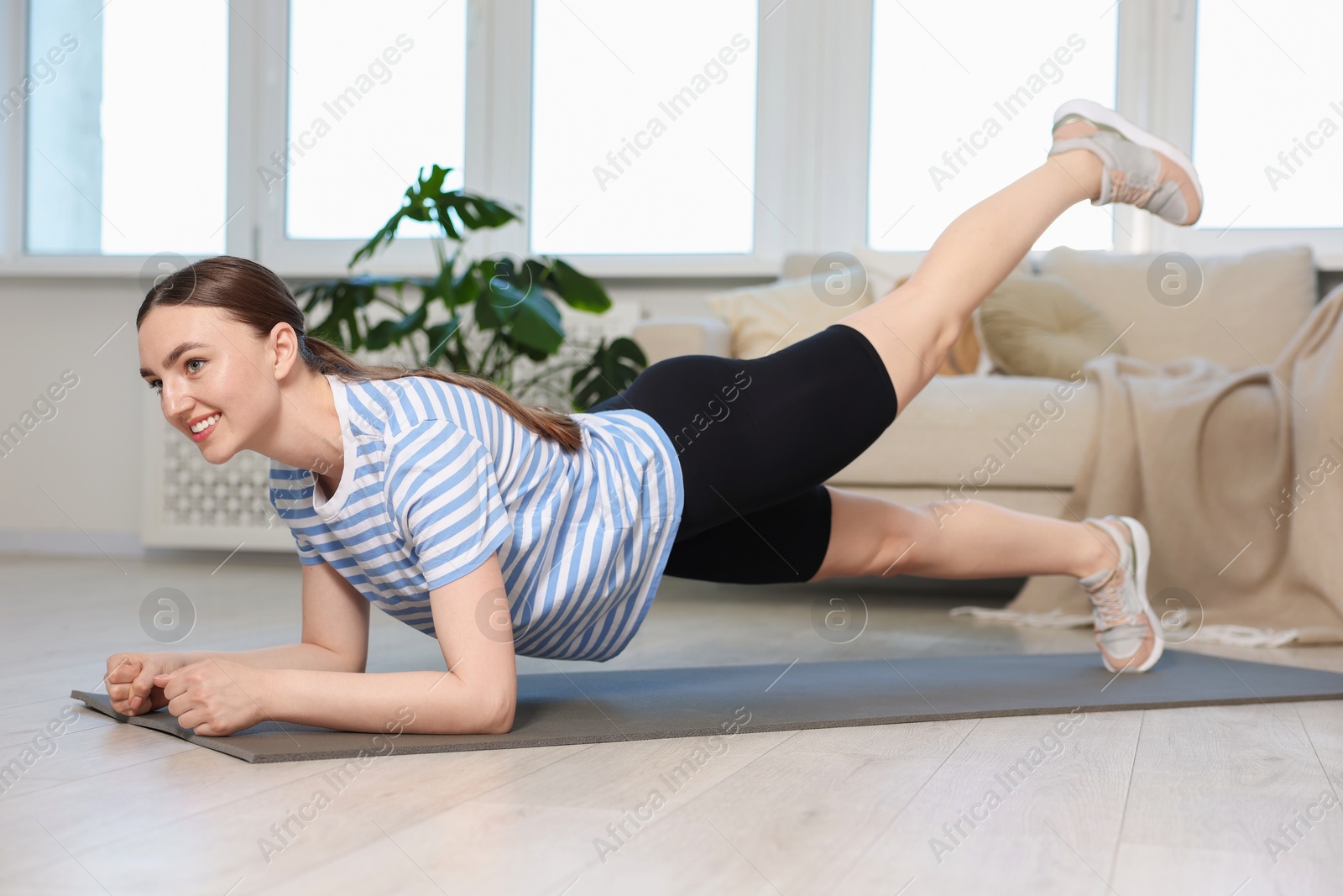 Smiling sporty woman doing plank exercise at home Photo of Smiling sporty woman doing plank exercise at home