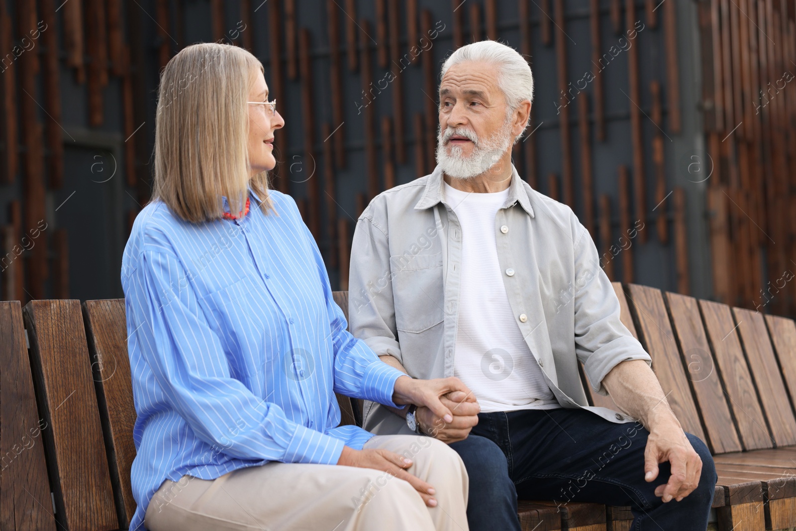 Lovely senior couple on bench near building outdoors Photo of Lovely senior couple on bench near building outdoors