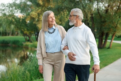 Photo of Lovely senior couple walking together near lake in park