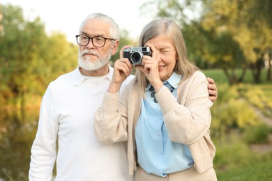 Photo of Lovely senior couple with vintage photo camera in park