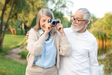 Photo of Lovely senior couple with vintage photo camera in park