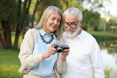 Photo of Lovely senior couple with vintage photo camera in park