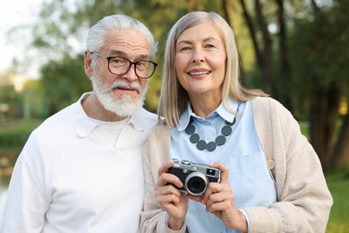 Photo of Lovely senior couple with vintage photo camera in park