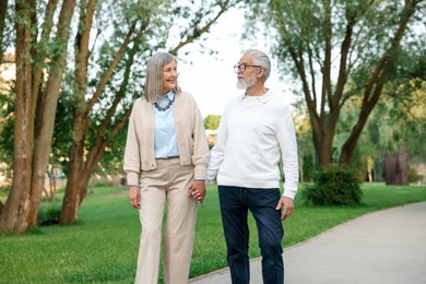 Photo of Lovely senior couple walking together in park