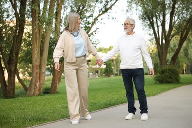 Photo of Lovely senior couple walking together in park