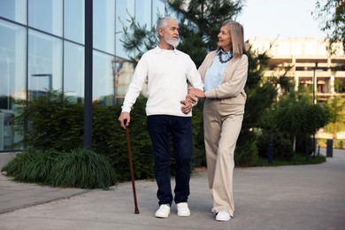 Photo of Lovely senior couple walking together near building outdoors