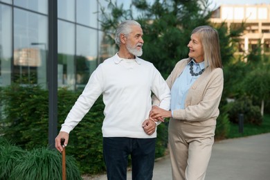 Photo of Lovely senior couple walking together near building outdoors